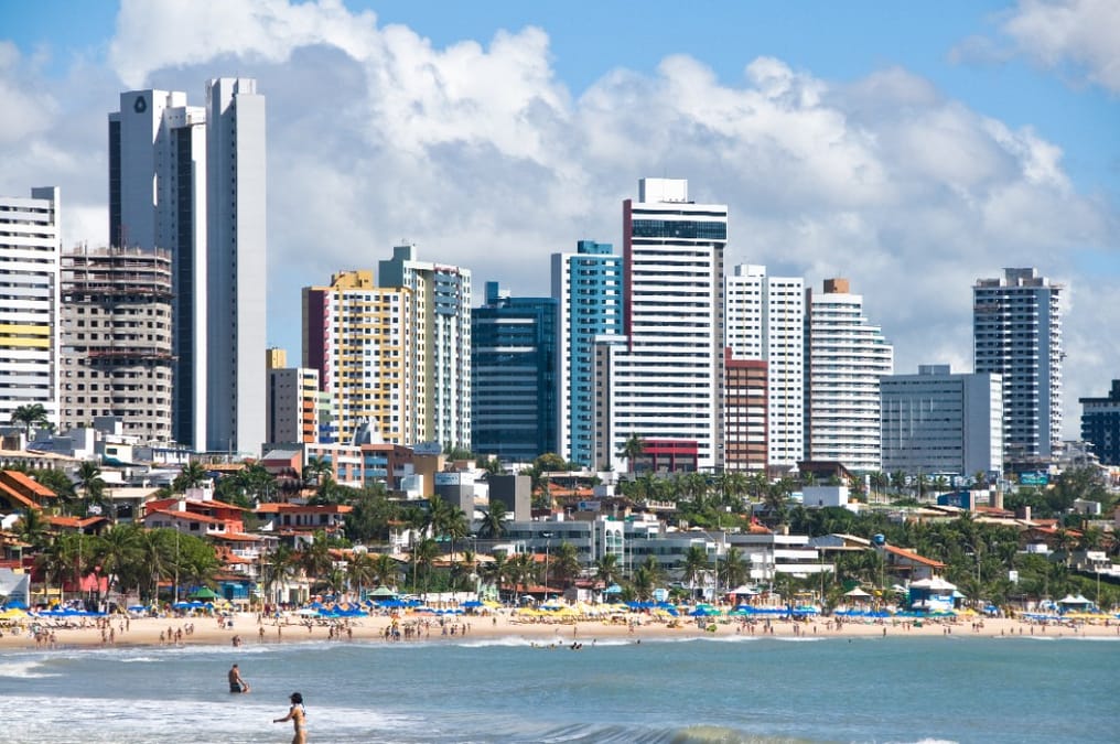 Praia de Ponta Negra em Natal: areia, guarda-sóis e prédios à beira-mar sob céu azul